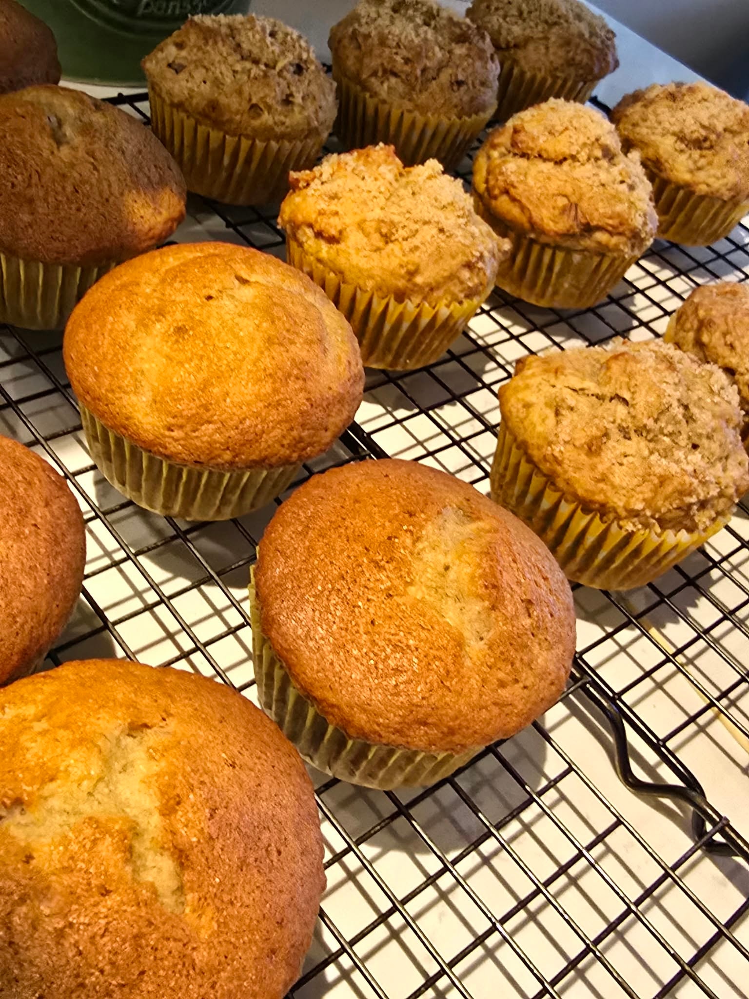 Two trays of freshly baked golden muffins on a cooling rack