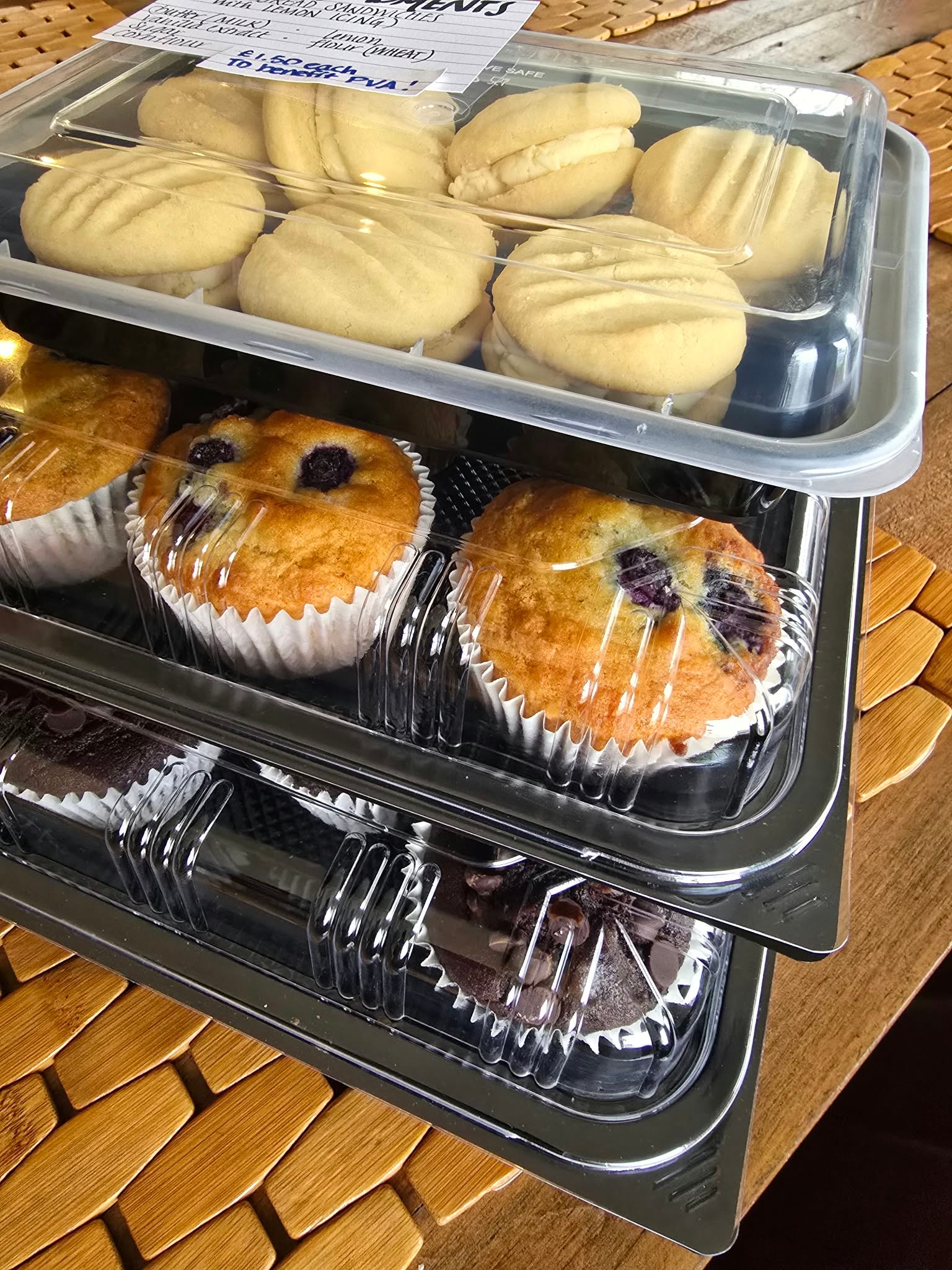 Stacked trays of blueberry muffins, sandwich cookies, and brownies